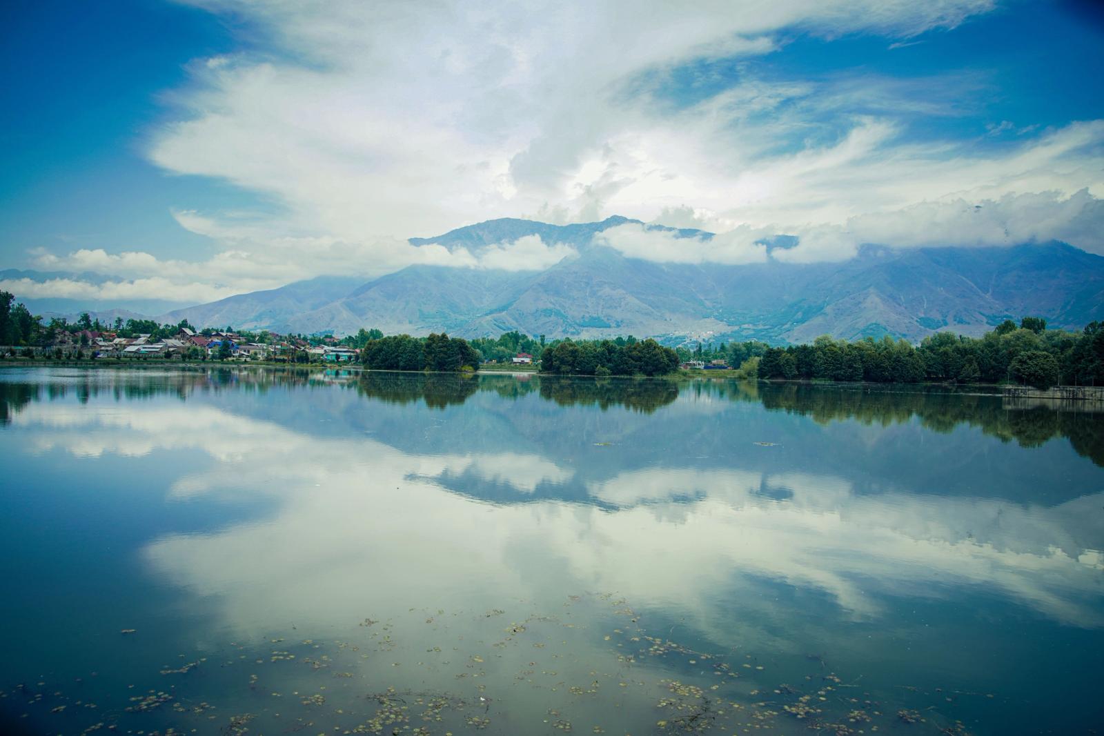 Peaceful landscape of Dal Lake with mountains and clear reflections in Srinagar, India