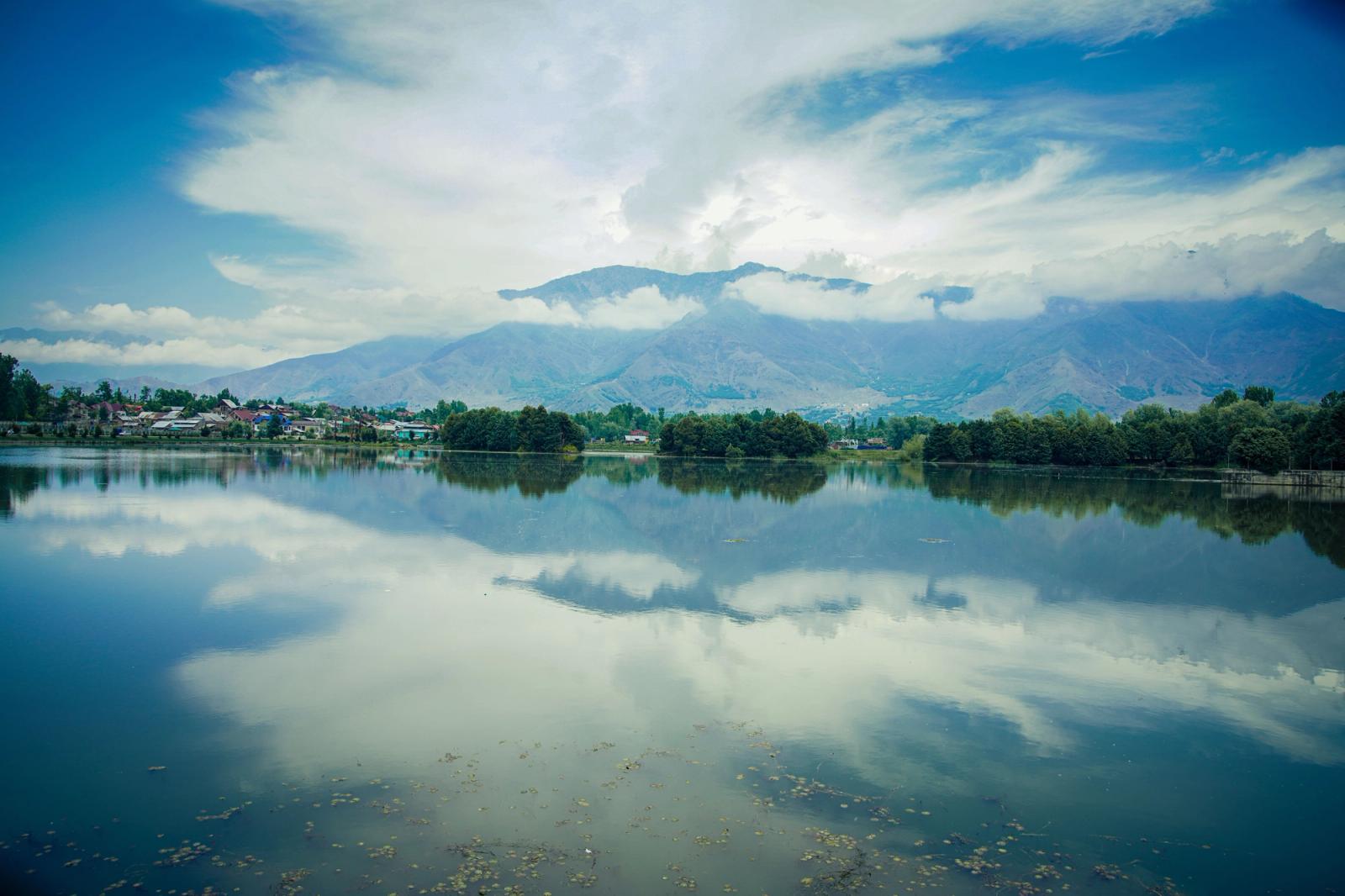 Peaceful landscape of Dal Lake with mountains and clear reflections in Srinagar, India