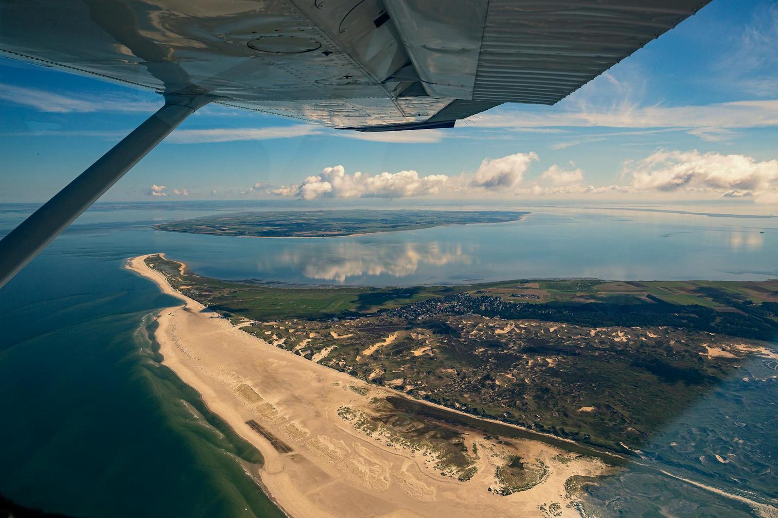 View from a small aircraft window over a sandy coastal peninsula