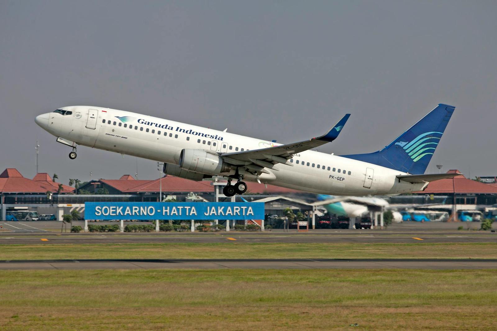 A passenger jet climbs after takeoff past an airport signboard