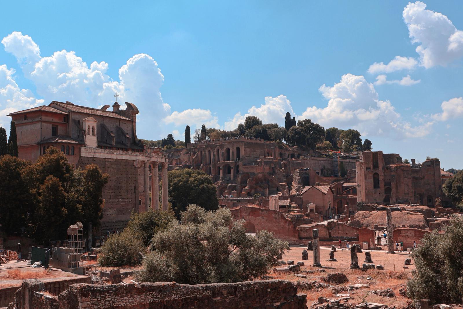 Explore ancient Roman ruins in Rome with clear skies, lush greenery, and historical architecture