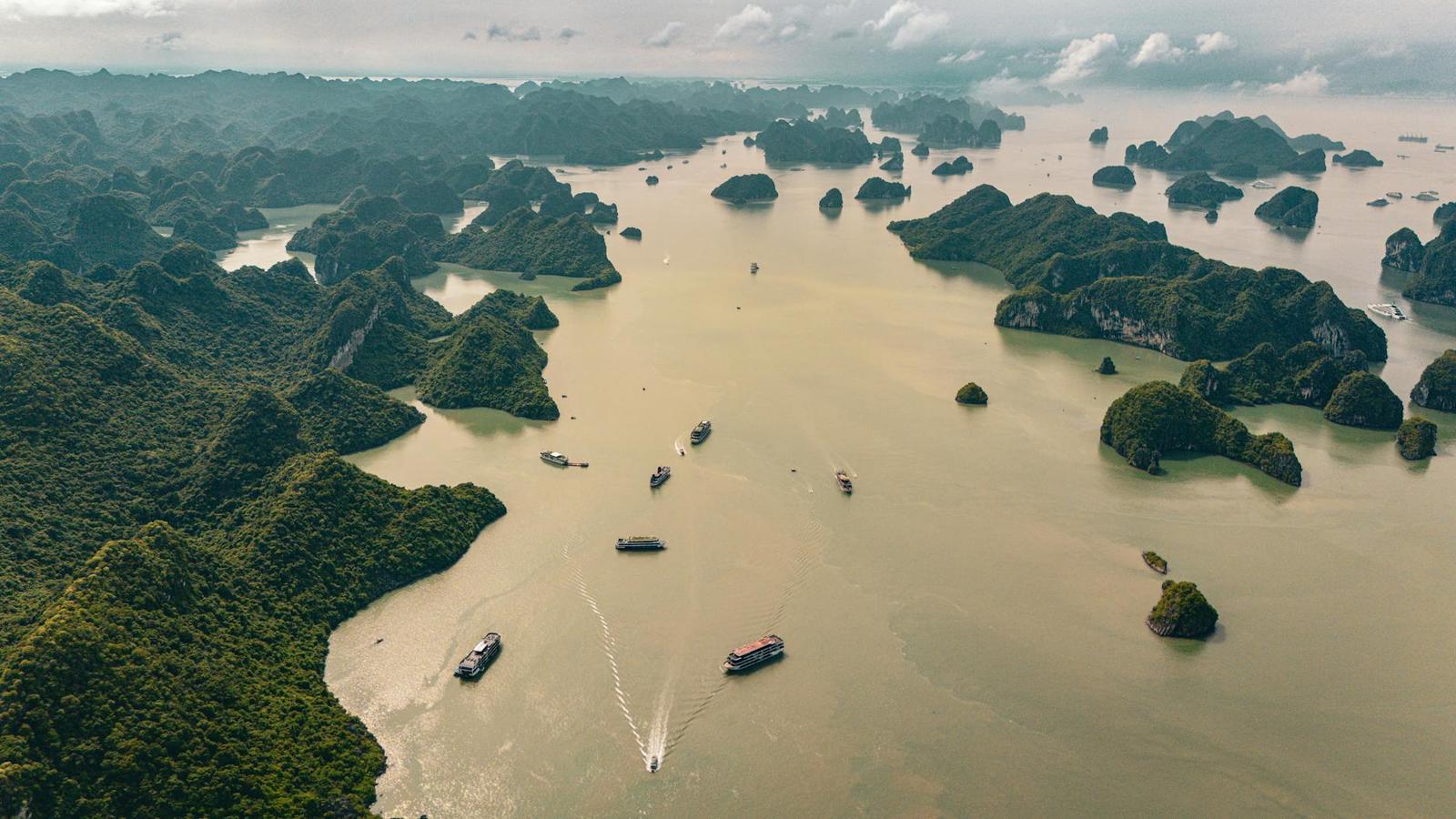Misty aerial view of limestone islets scattered across a bay with small boats