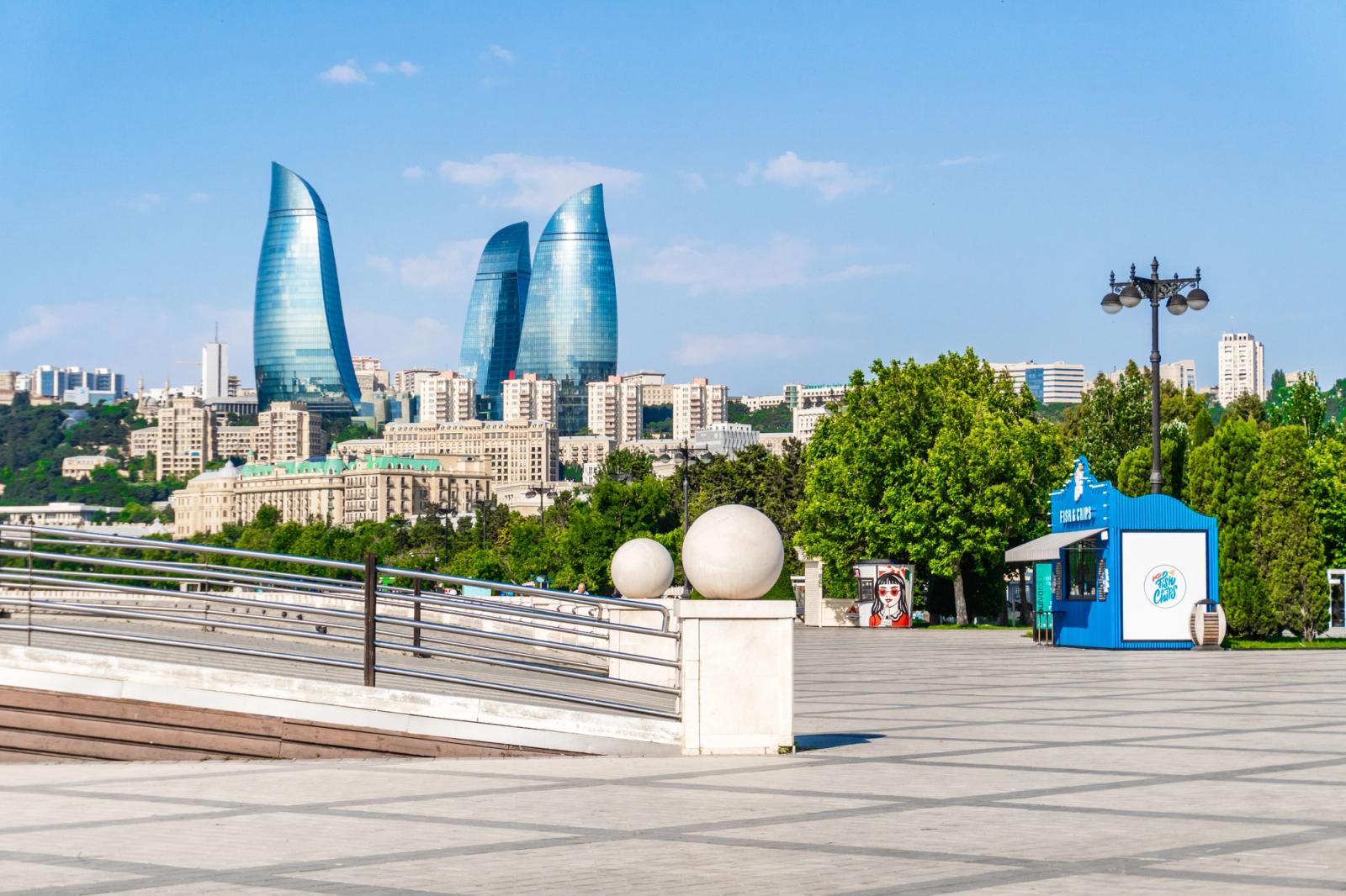 View of Baku Flame Towers with lush trees and city skyline