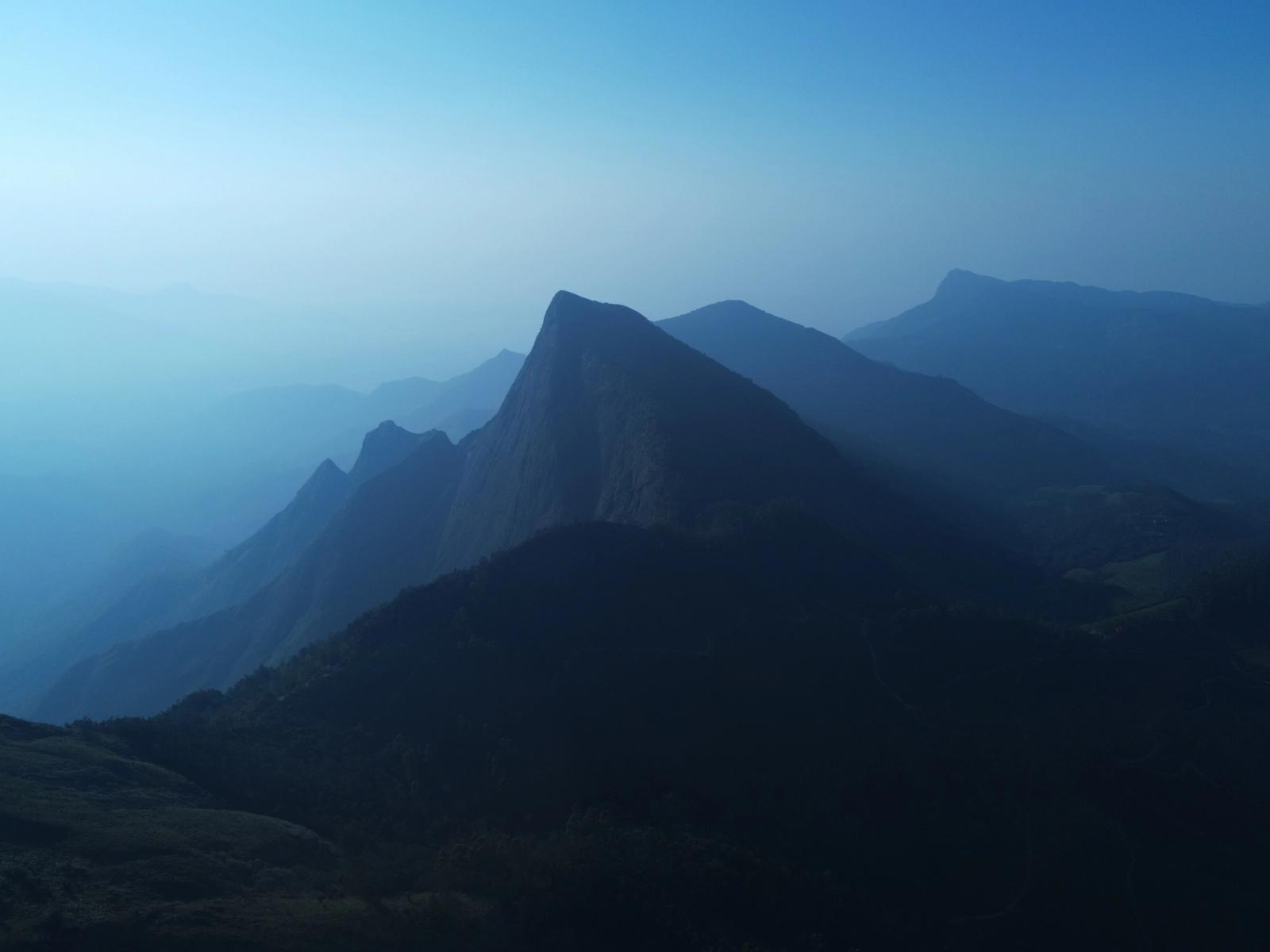 Scenic view of mountain peaks enveloped in mist at Suryanelli, India, creating a tranquil landscape