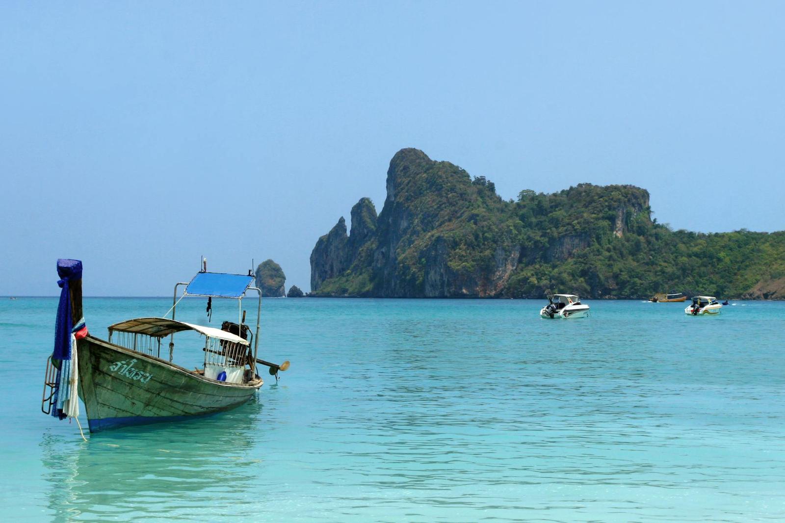 Longtail boat anchored near a rocky island in clear water