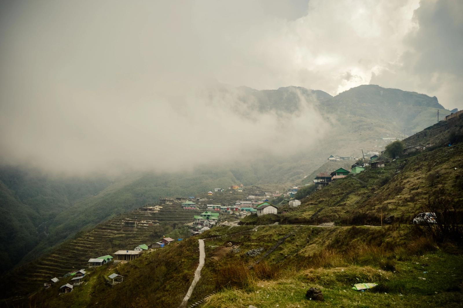 Serene landscape of a mist-covered village nestled among the hills of Sikkim, India