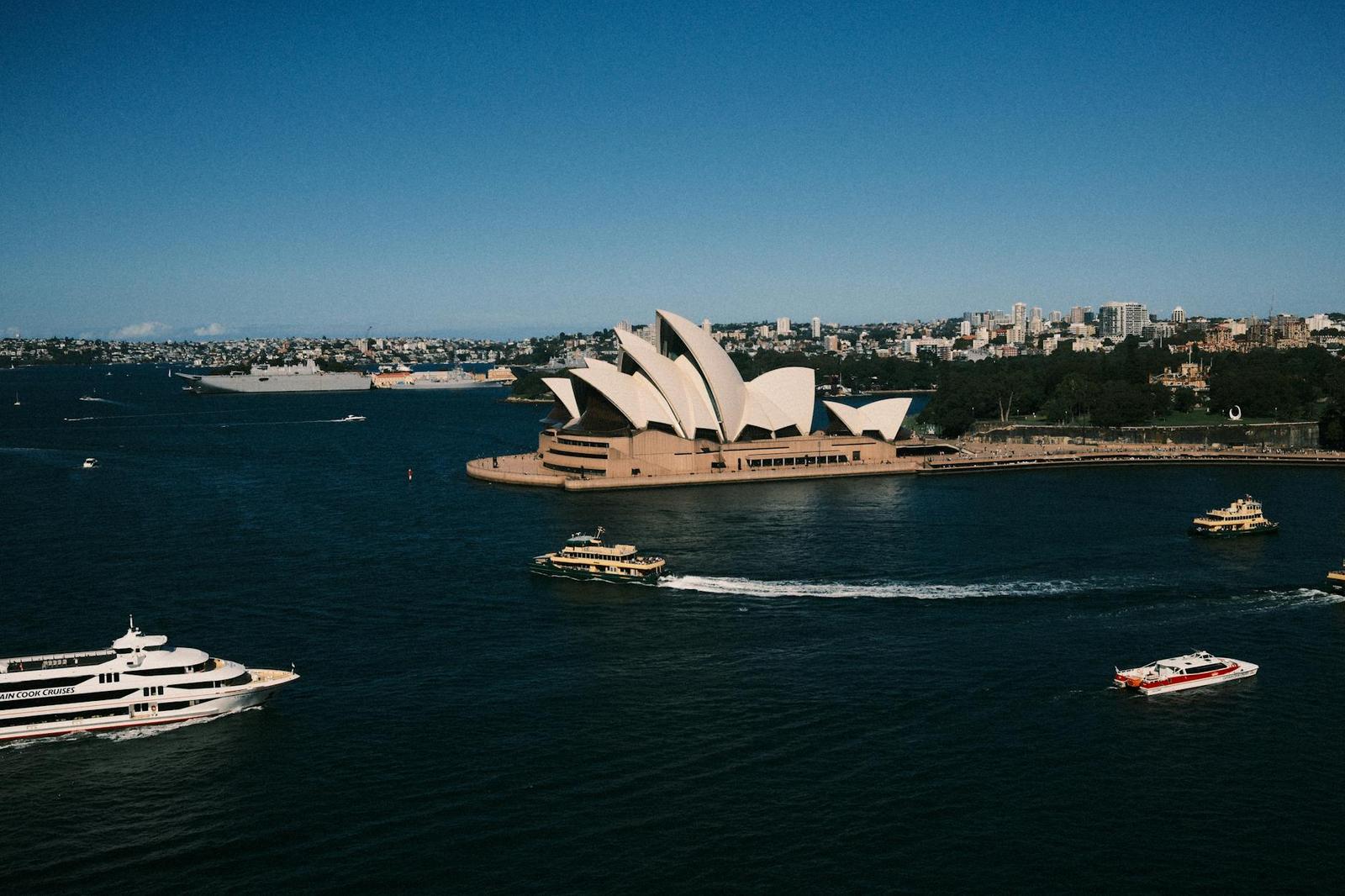 Ferries cross the harbour past the Sydney Opera House's white sail roofs