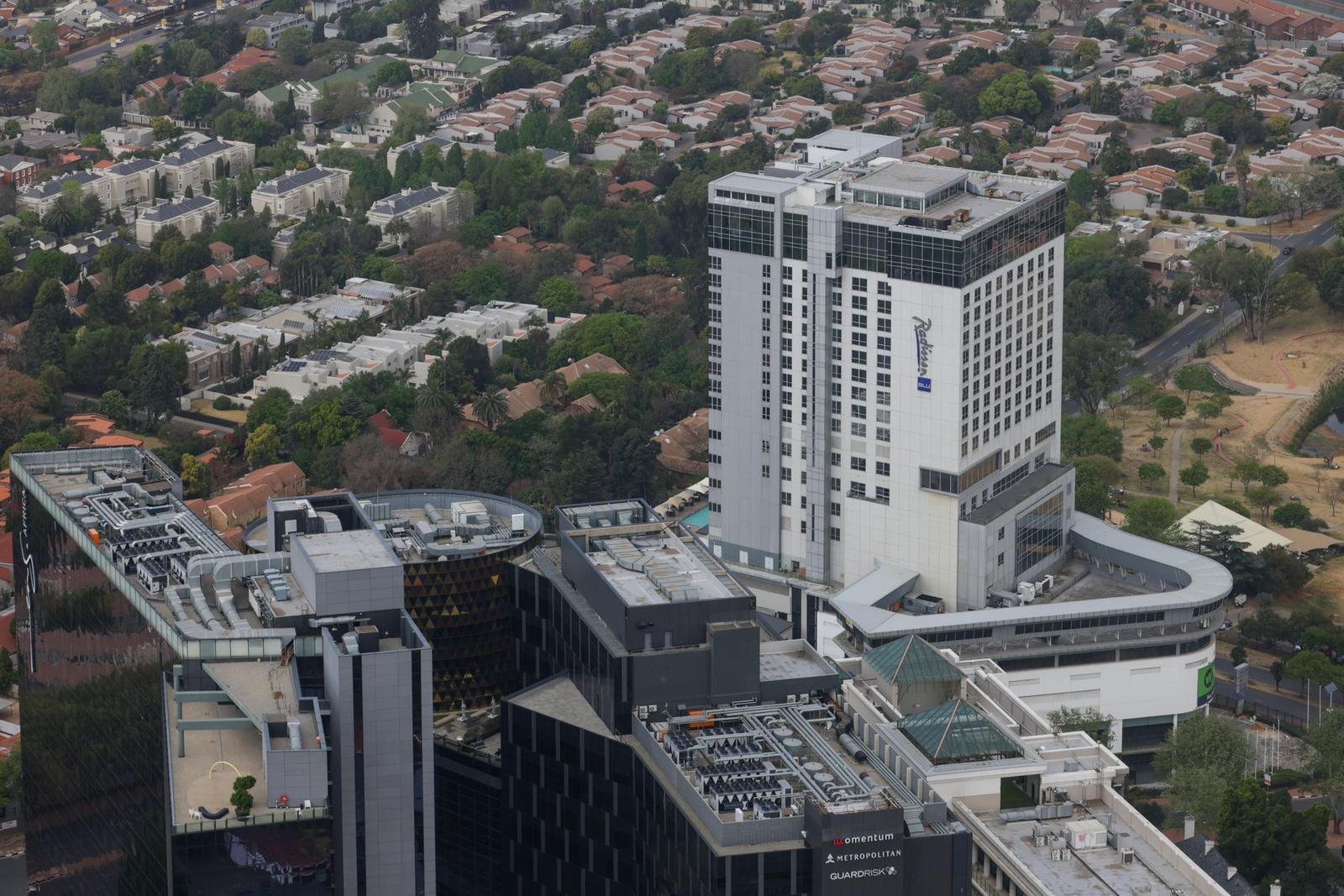 An aerial view of a tall hotel tower surrounded by lower office blocks with rooftop terraces