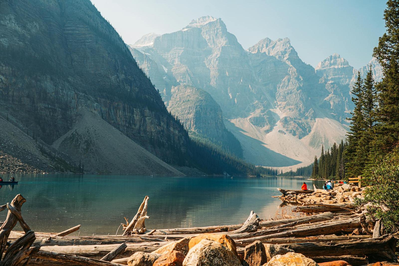 Turquoise glacial lake framed by jagged mountains with small boats near the shore
