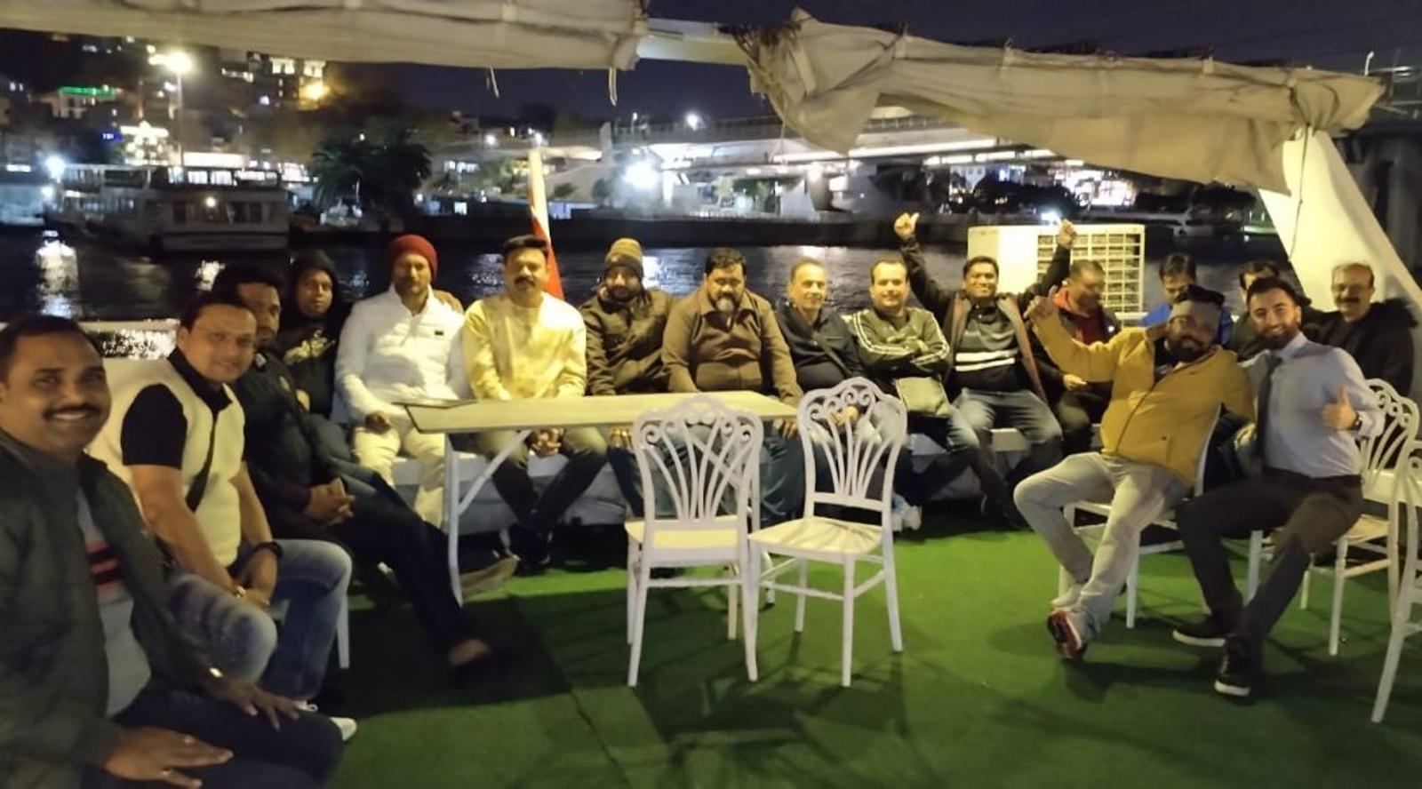 Group of people sitting on a boat with city lights in the background.