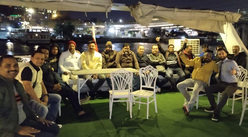Group of people sitting on a boat with city lights in the background.