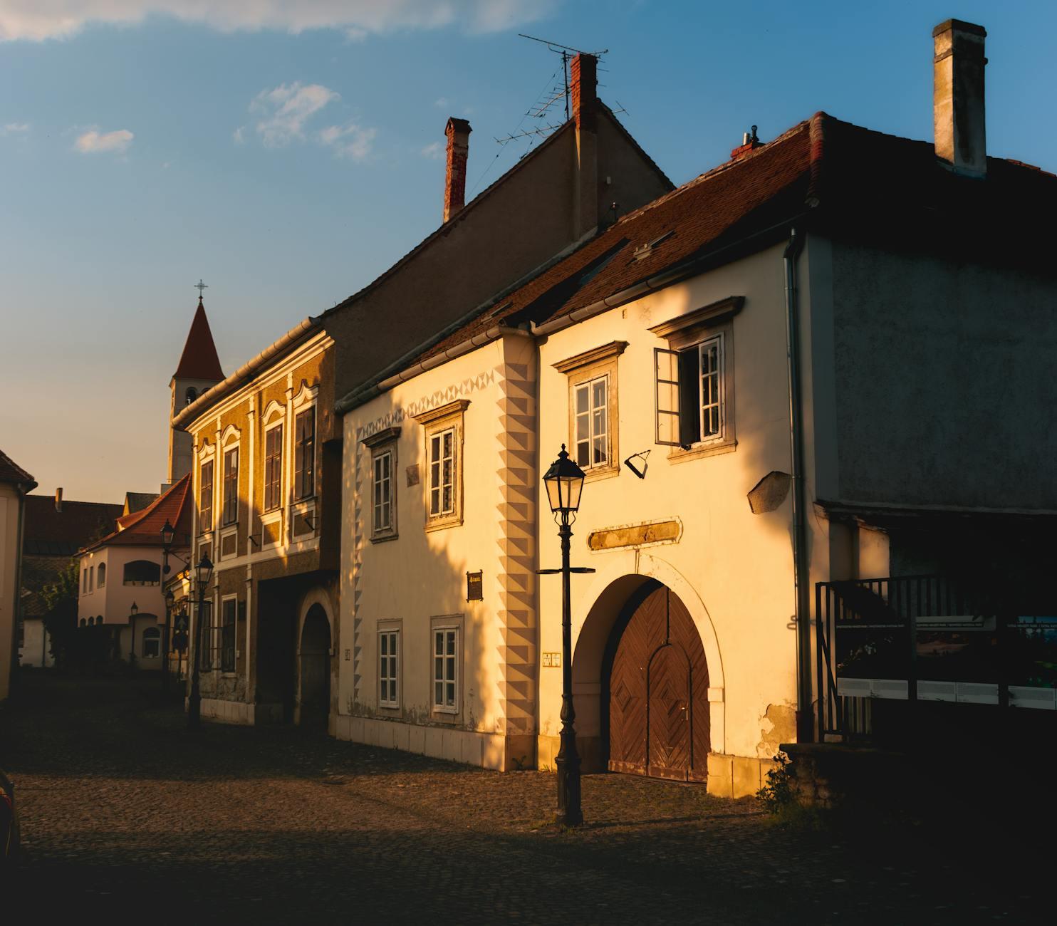 A cobblestone village street lined with pastel houses at golden hour