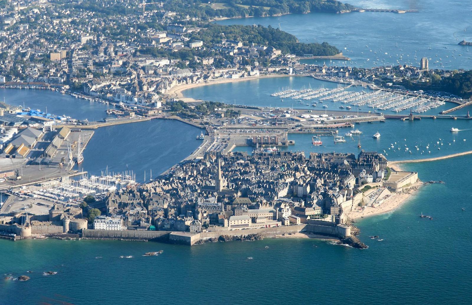 Aerial view of a walled coastal town with a marina and beach