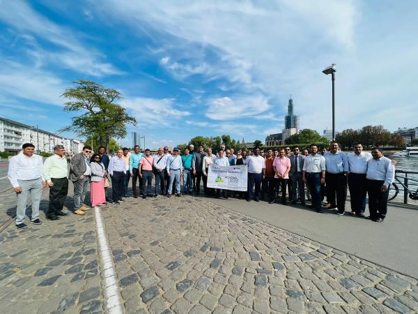 Large group posing outdoors on a cobblestone path with a banner.