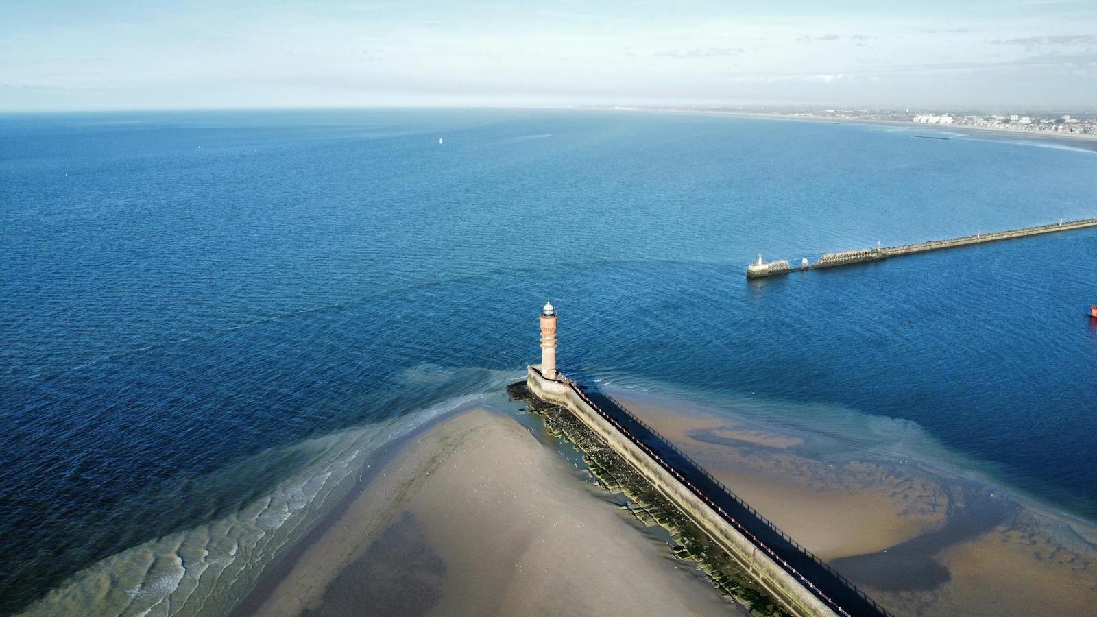 Aerial view of a lighthouse at the end of a long harbour breakwater