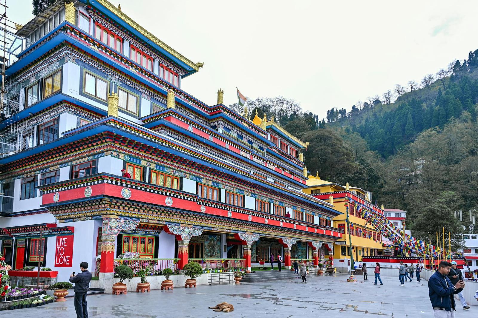 A colorful monastery courtyard with a few visitors and a dog resting