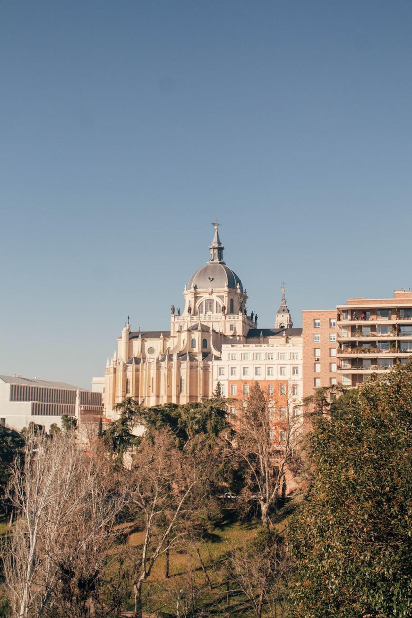 Almudena Cathedral in Madrid, Spain, captured in a sunlit urban setting against a clear sky