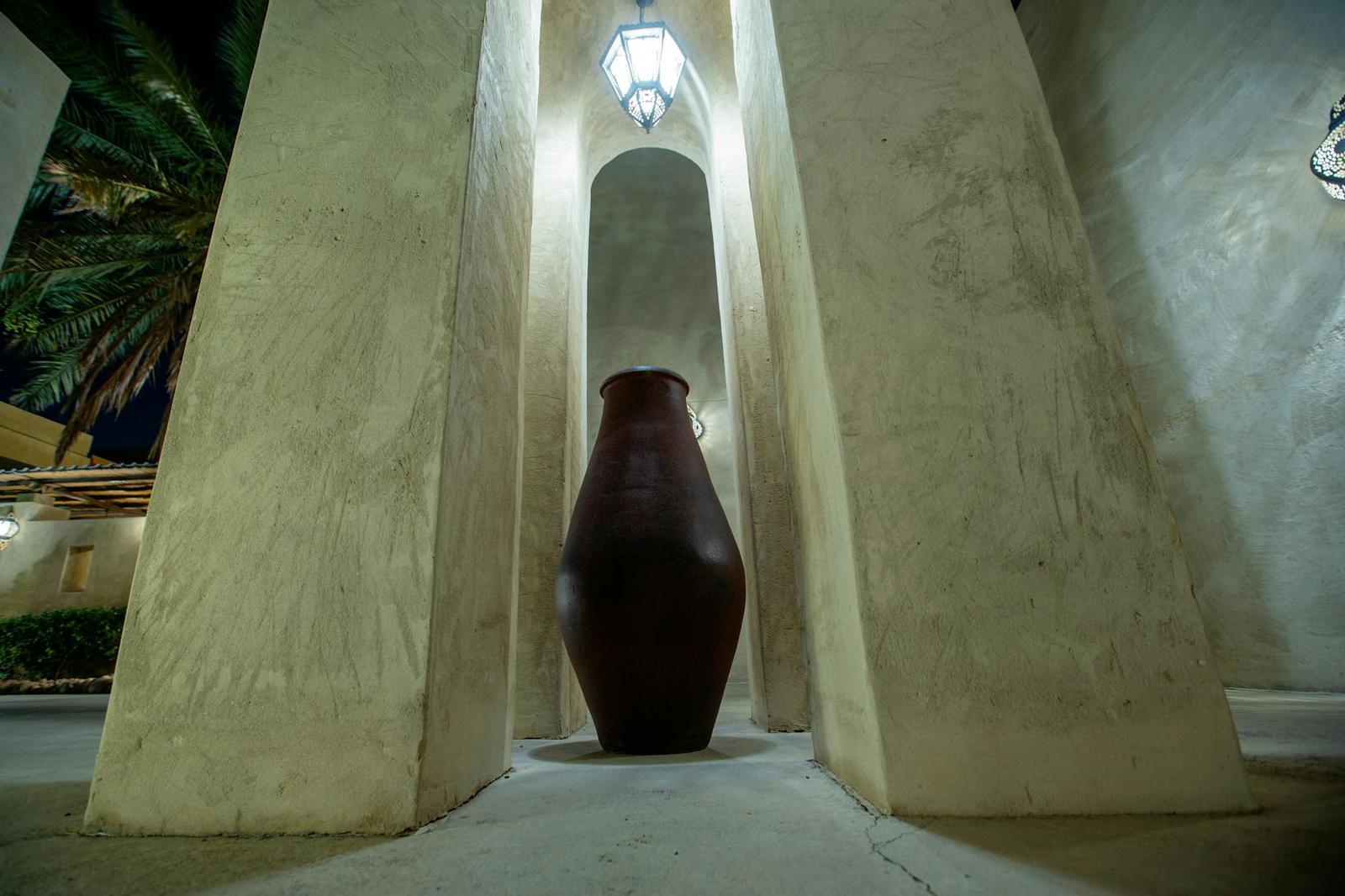 A large clay jar set in a lantern-lit stone alcove at a heritage hotel