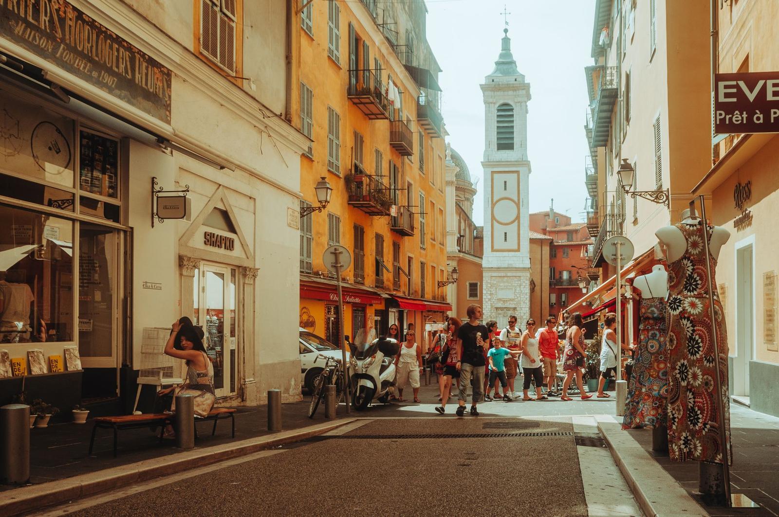 Bustling European street scene with tourists, shops, and a picturesque church tower