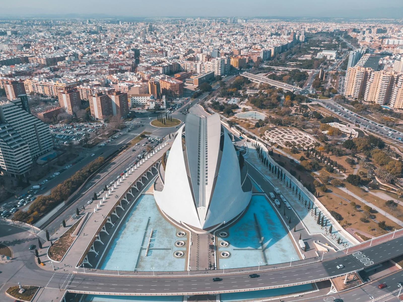 Aerial view of a futuristic white arts complex beside long reflecting pools