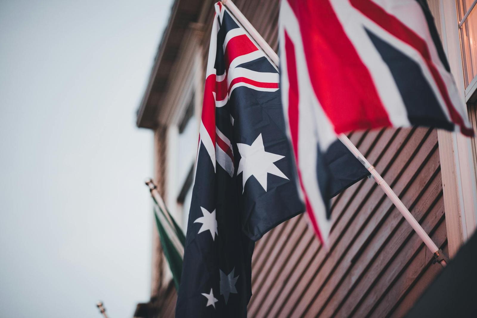 Two national flags flutter against a timber building facade