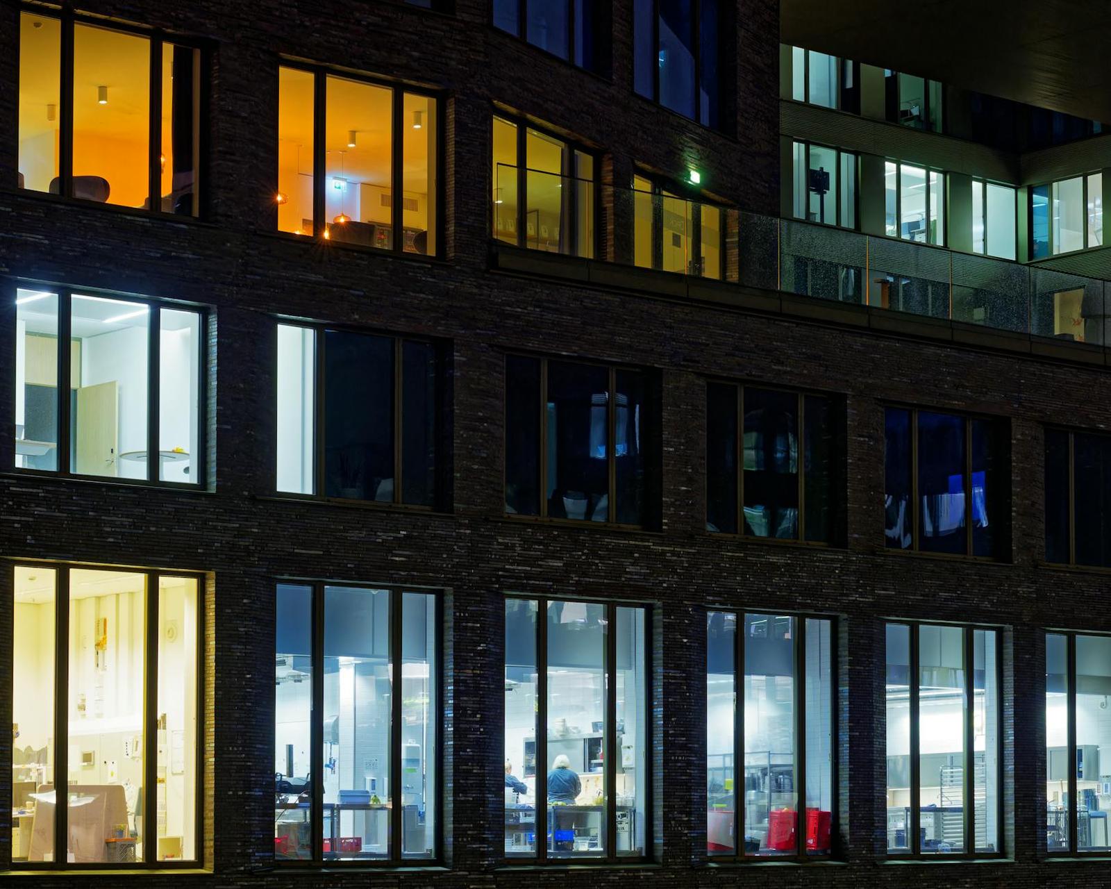 Lit apartment windows across a dark brick building facade at night