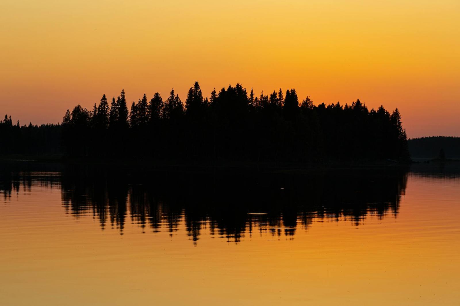 Captivating sunset reflection over a tranquil lake in Rovaniemi, Lapland, Finland