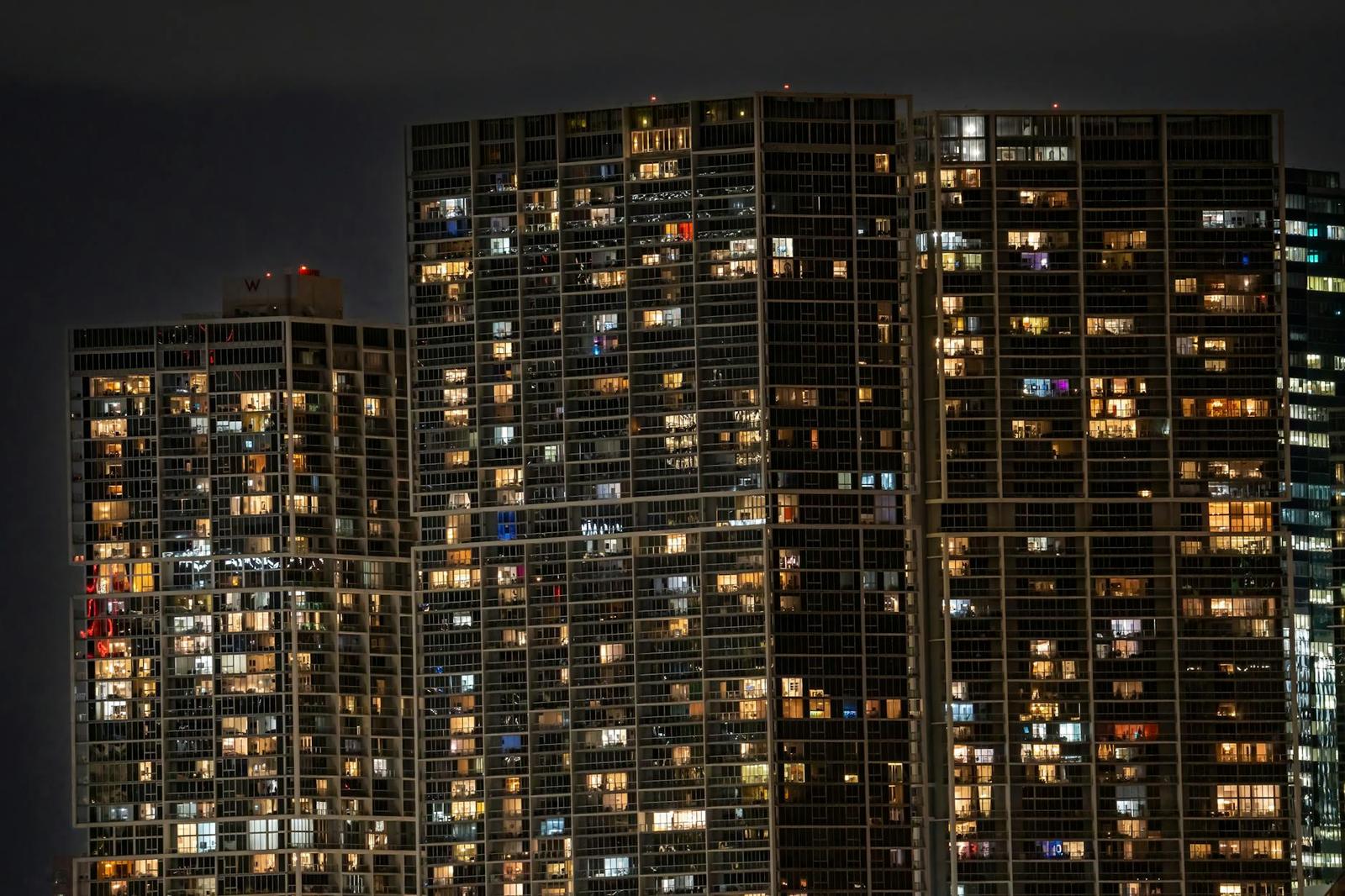 Illuminated windows across a cluster of high-rise apartment towers at night