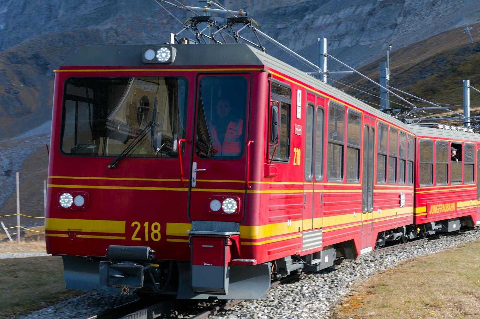 Red Jungfraubahn train traveling through the Swiss Alps in daylight