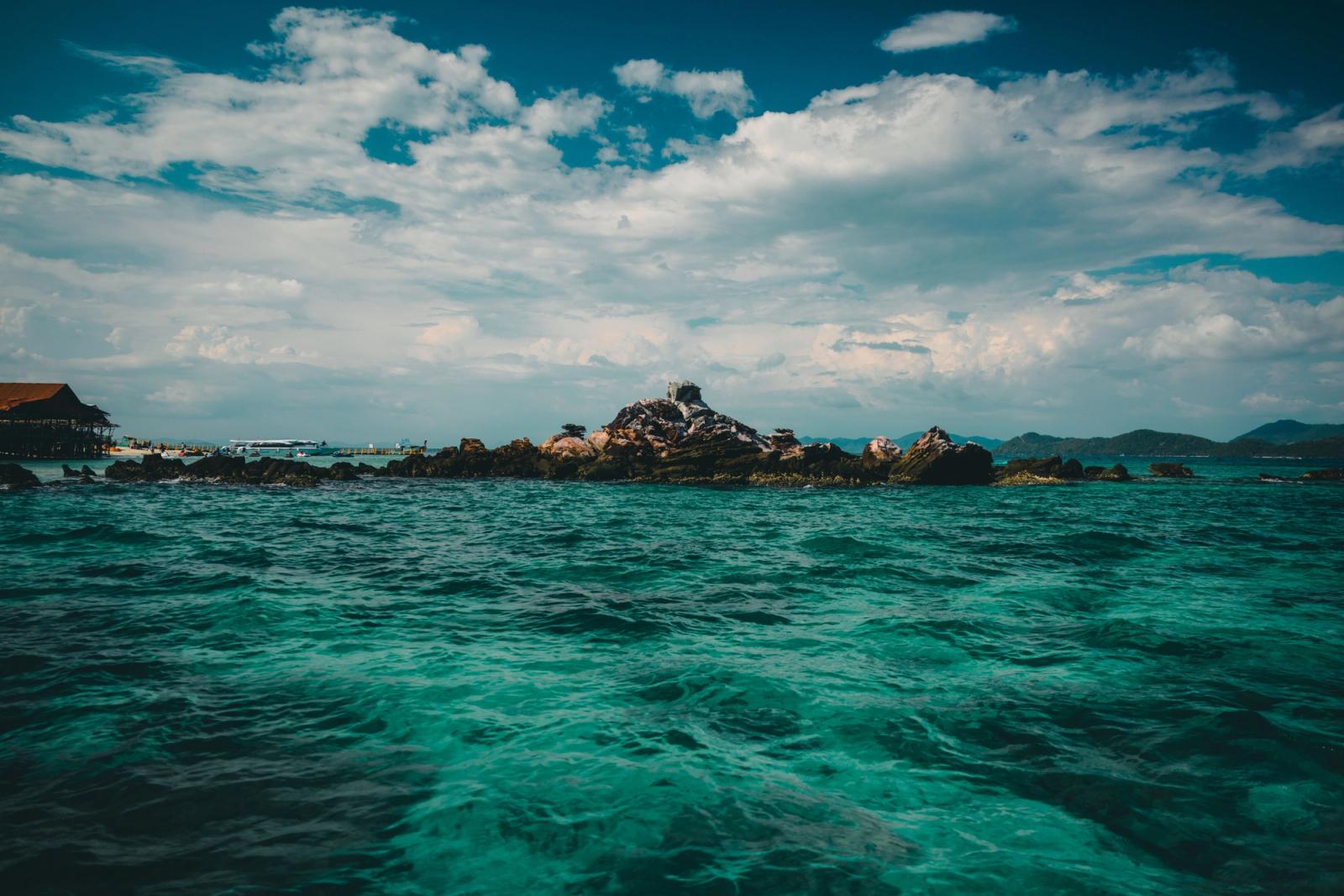 Breathtaking view of a rocky island in the turquoise sea of Phuket, Thailand under a dramatic sky