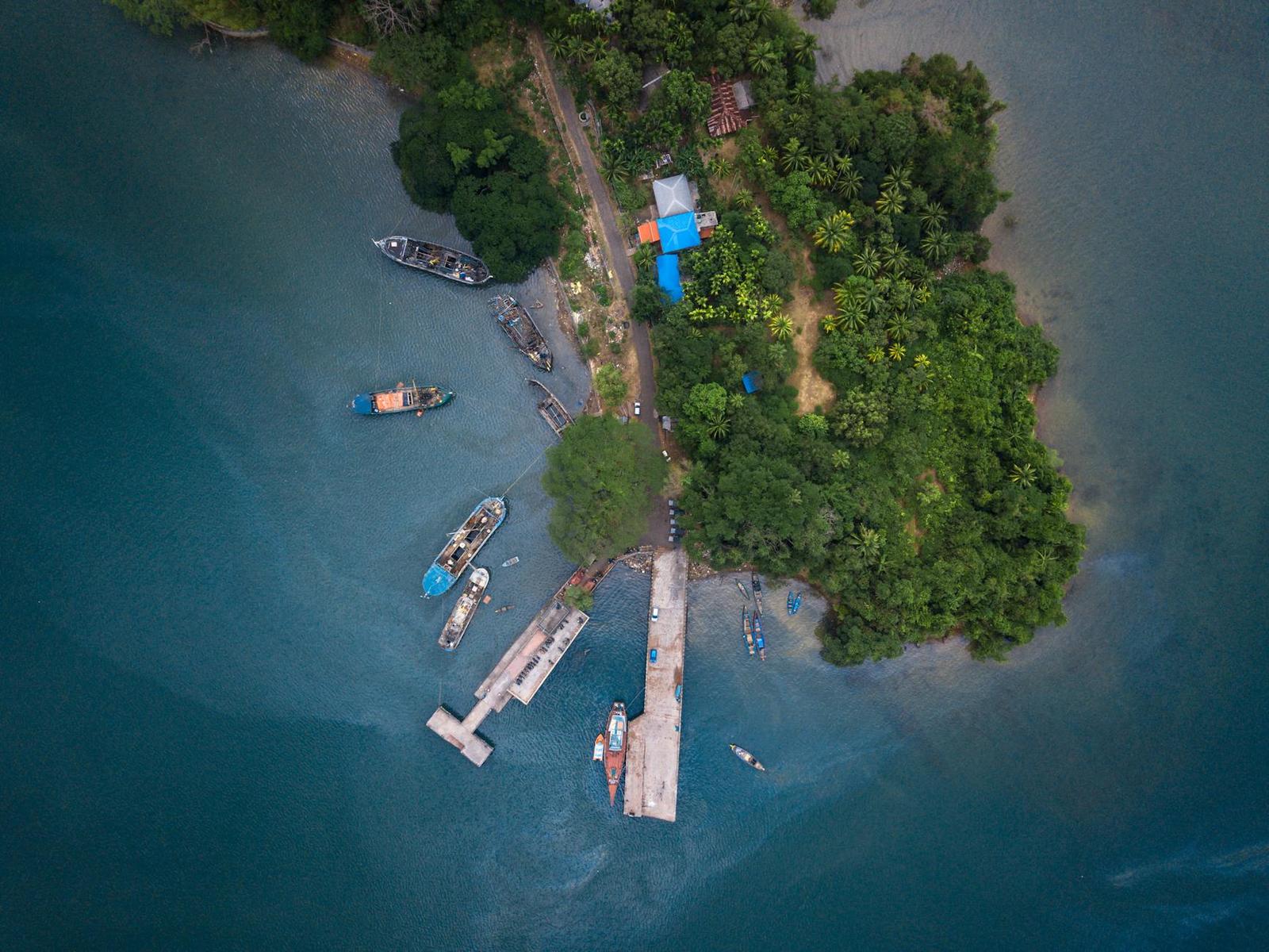 Aerial view of a wooded island with boats moored beside a jetty