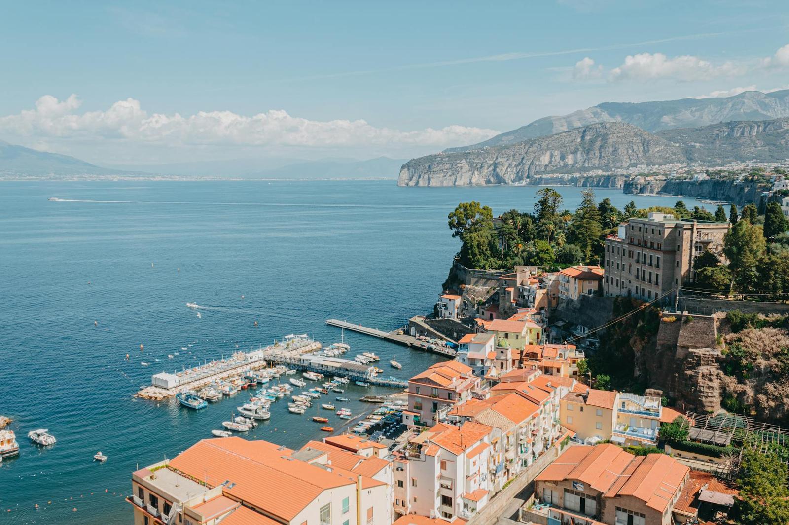 Aerial view of a colourful cliffside harbour town on a coastal bay