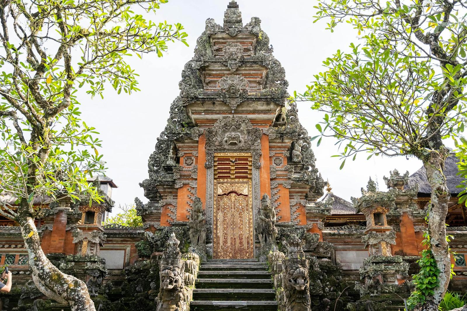 A detailed stone entrance of a traditional Balinese temple surrounded by lush greenery in Ubud
