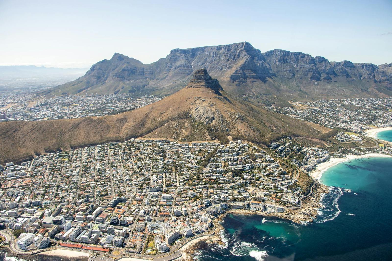 Aerial view of a coastal city framed by dramatic mountain ranges