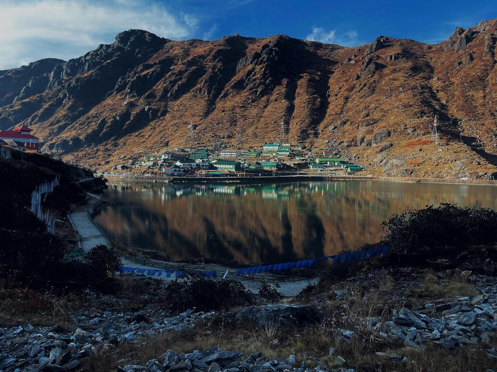 Mountainside settlement with colorful rooftops reflected in a still lake
