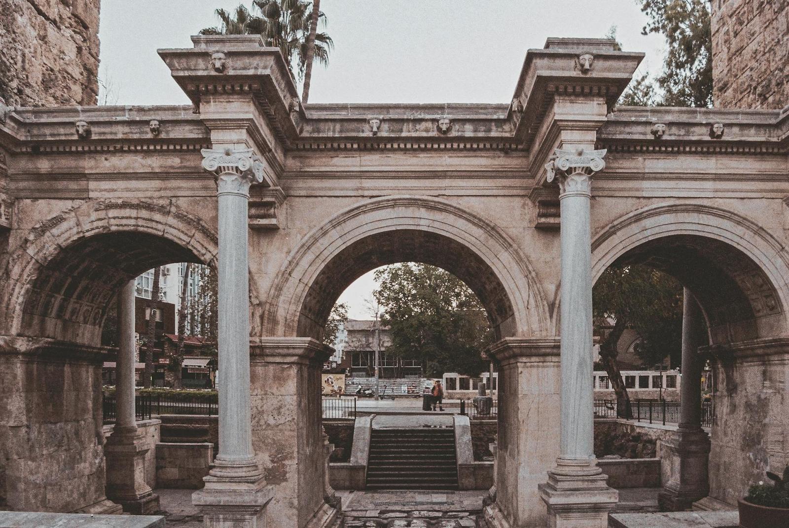 Explore an iconic Roman arch with classic columns in an urban cityscape