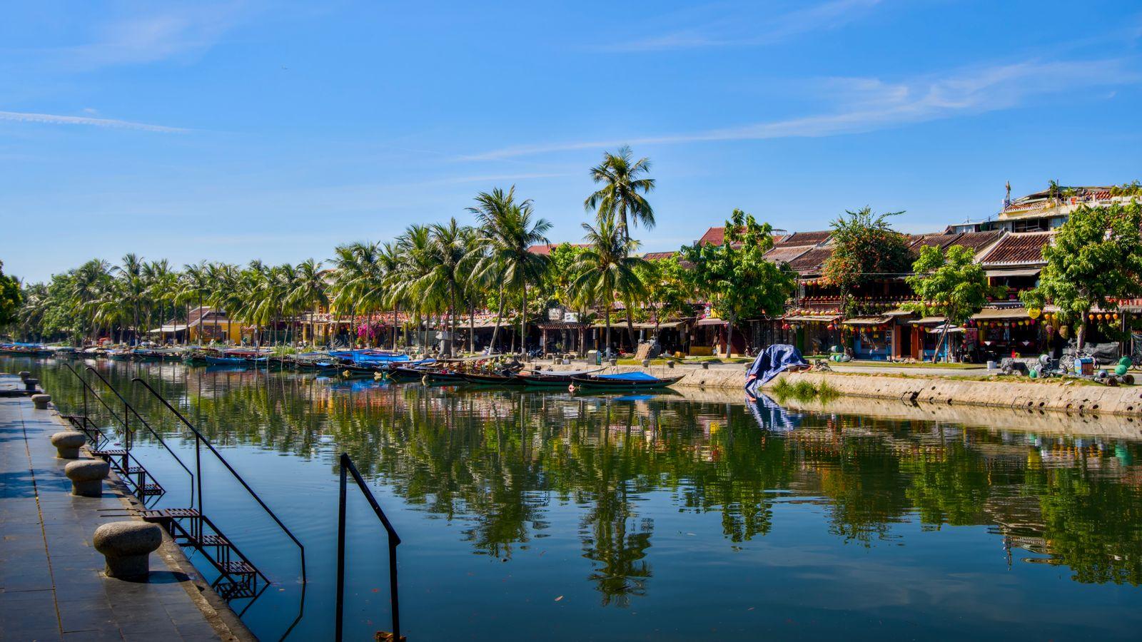 The Hoi An riverfront with moored boats and old-town rooftops