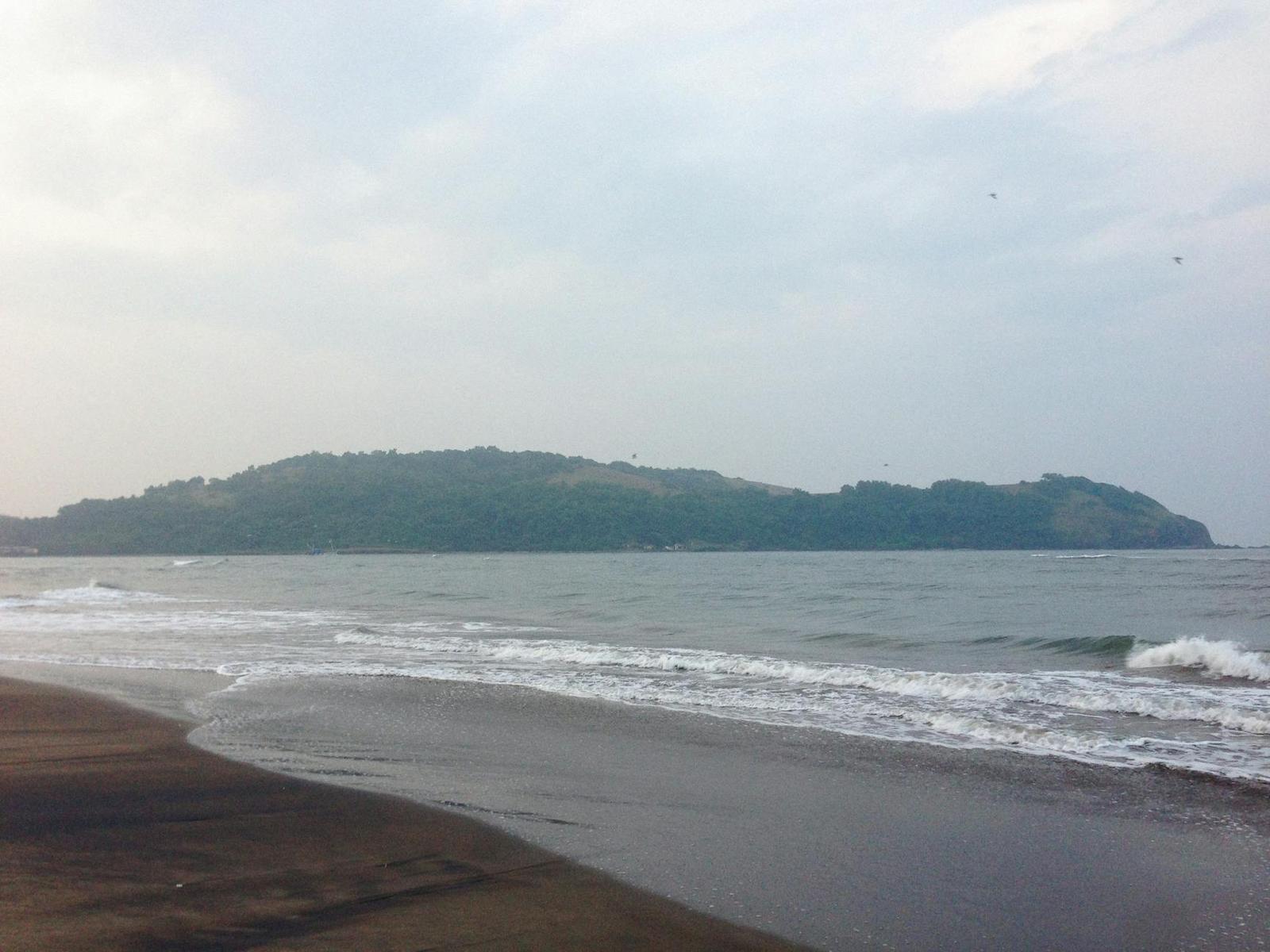 A hazy forested headland seen across a calm bay
