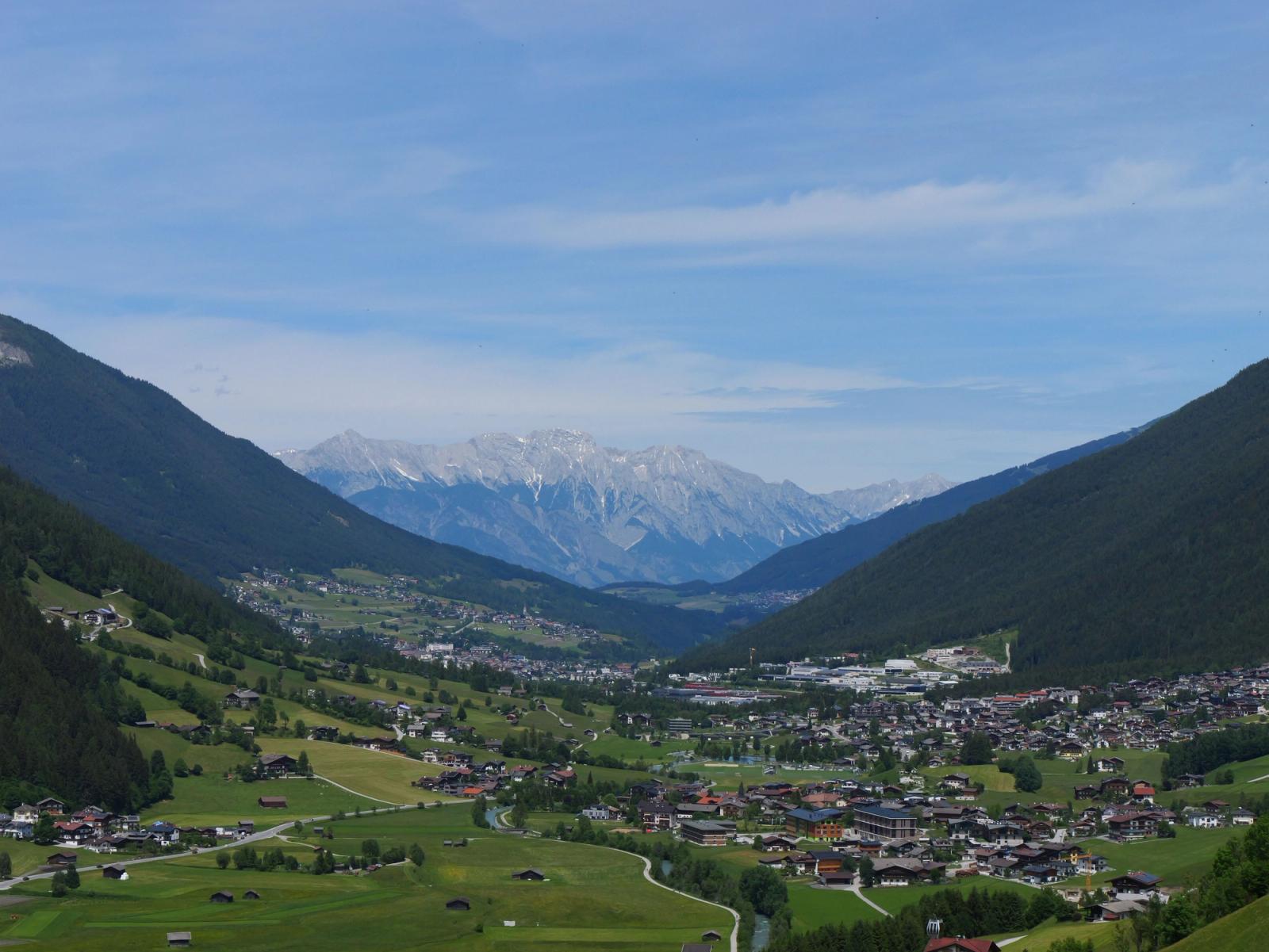 Breathtaking panoramic view of a lush alpine valley with distant mountain range in summer