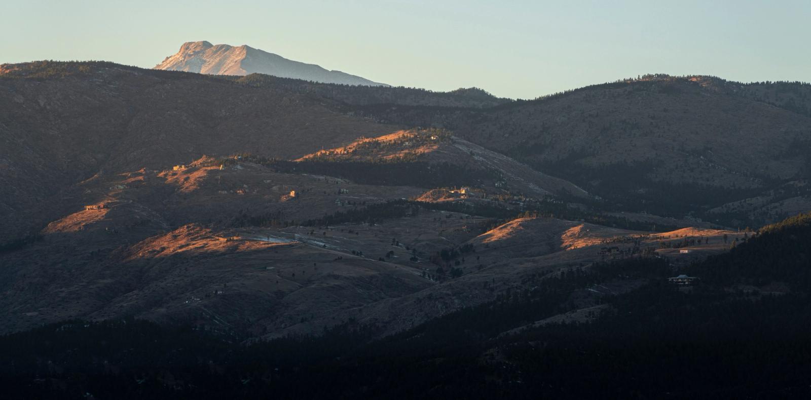 Captivating view of Colorado's mountains with warm sunset light casting shadows across the ridges