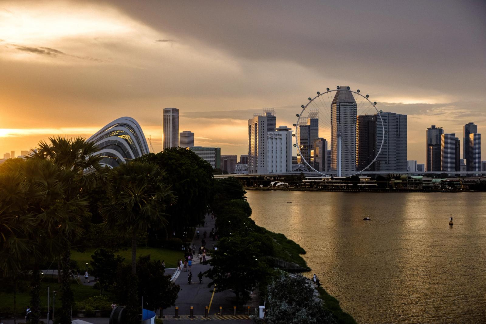 A stunning sunset view of the Singapore skyline featuring the iconic Ferris wheel and lush greenery