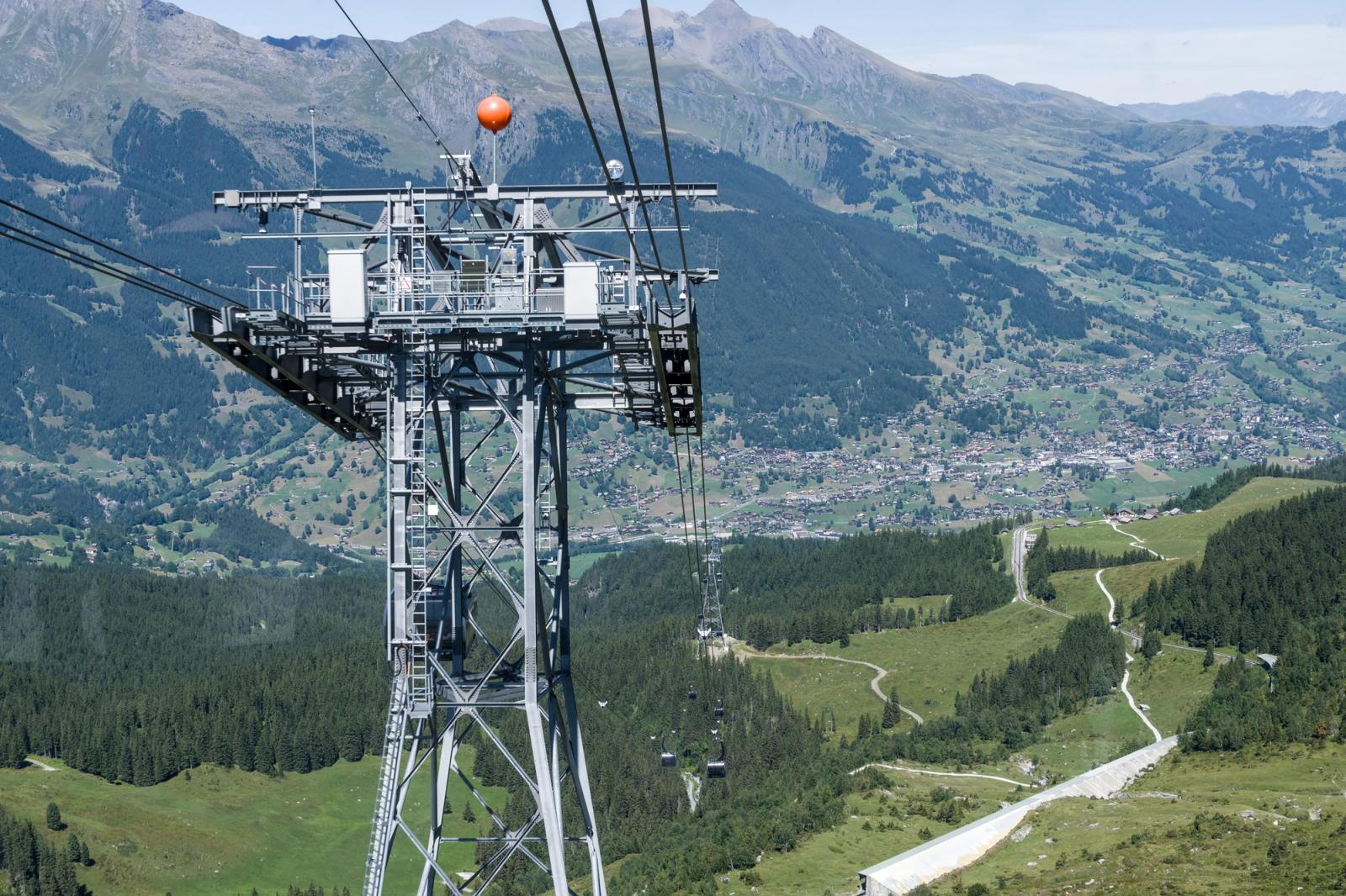 Breathtaking aerial view of a cableway tower overlooking a Swiss mountain village