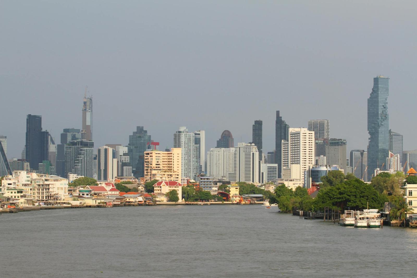 A river bend with a city skyline of towers under a hazy sky