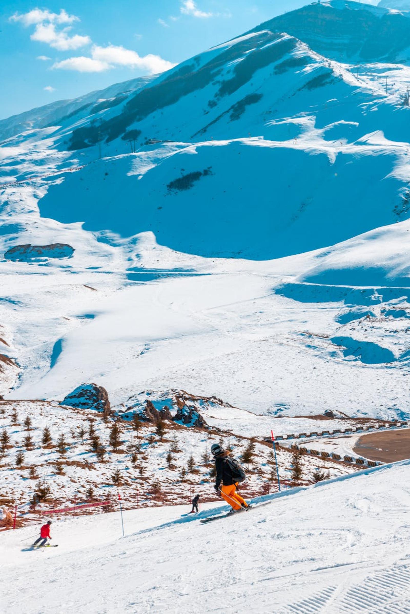 Skiers enjoying the snow-covered mountains near Baku, Azerbaijan under a bright blue sky