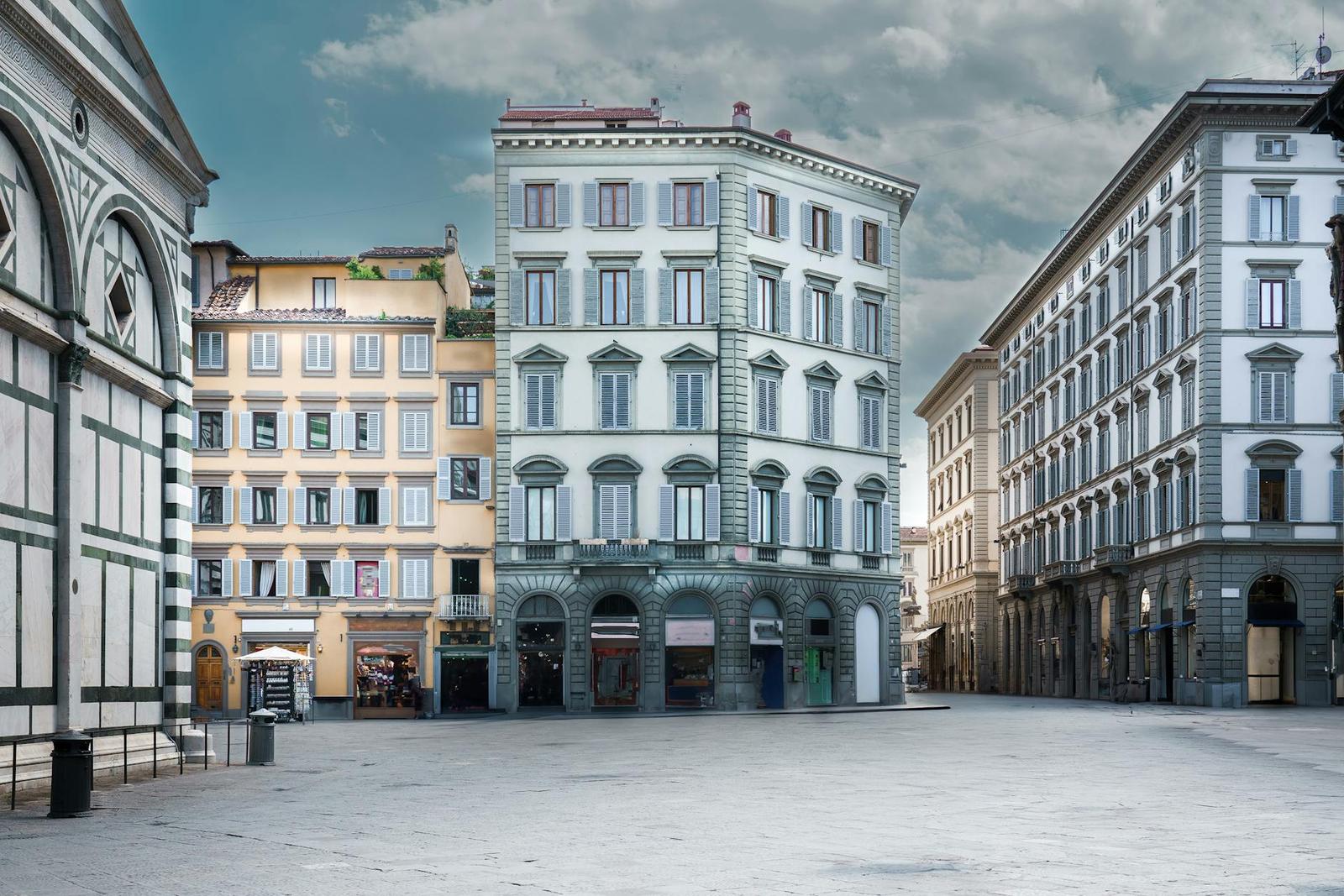 An empty stone piazza framed by historic multi-storey buildings