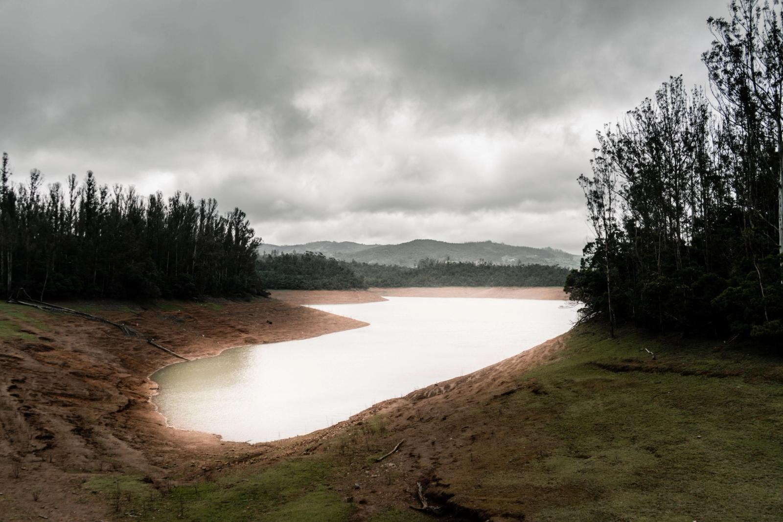 A beautiful view of Ooty Lake surrounded by lush trees on a cloudy day in Tamil Nadu, India