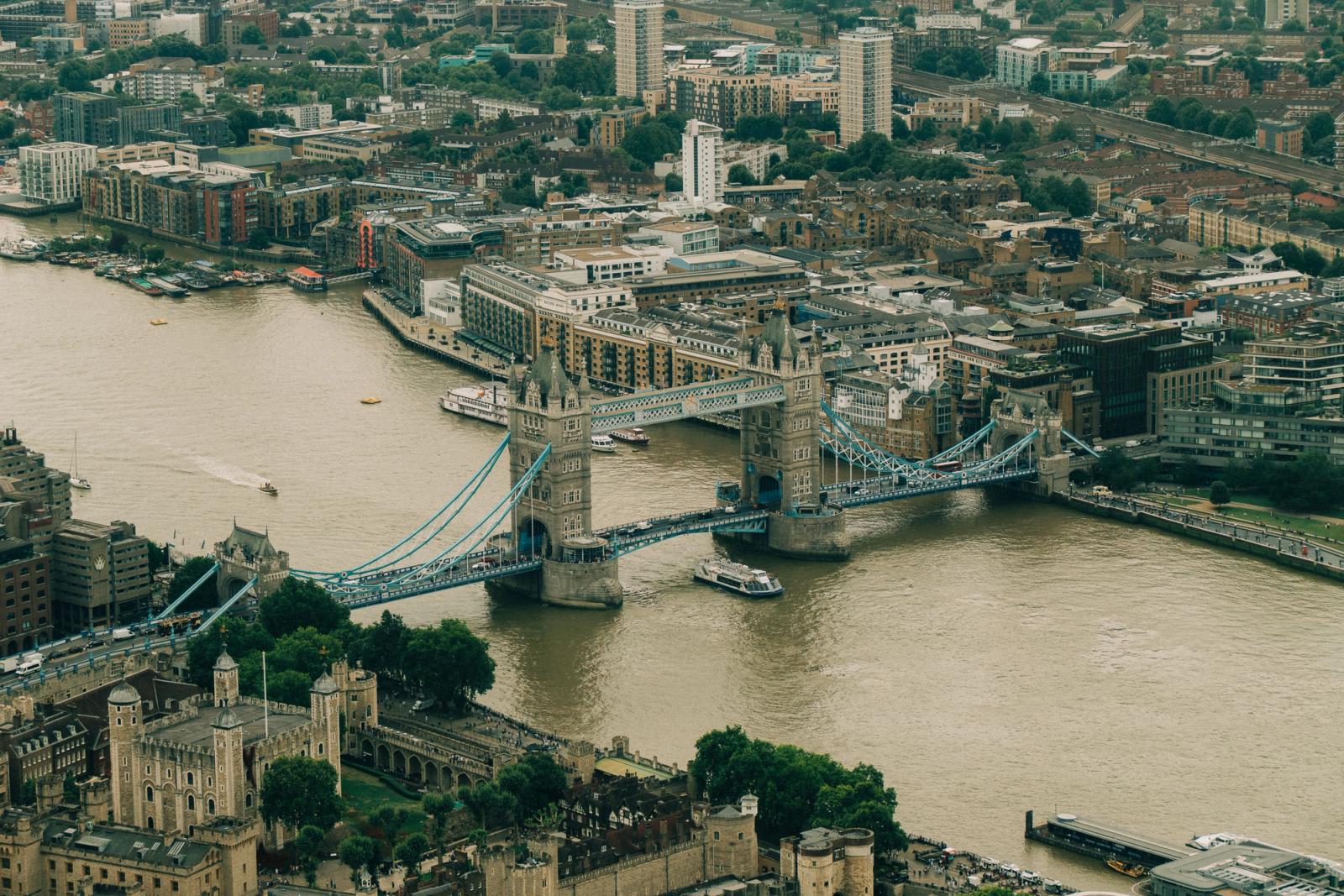 Aerial view showcasing the Tower Bridge over the Thames River in London, UK amidst urban landscape