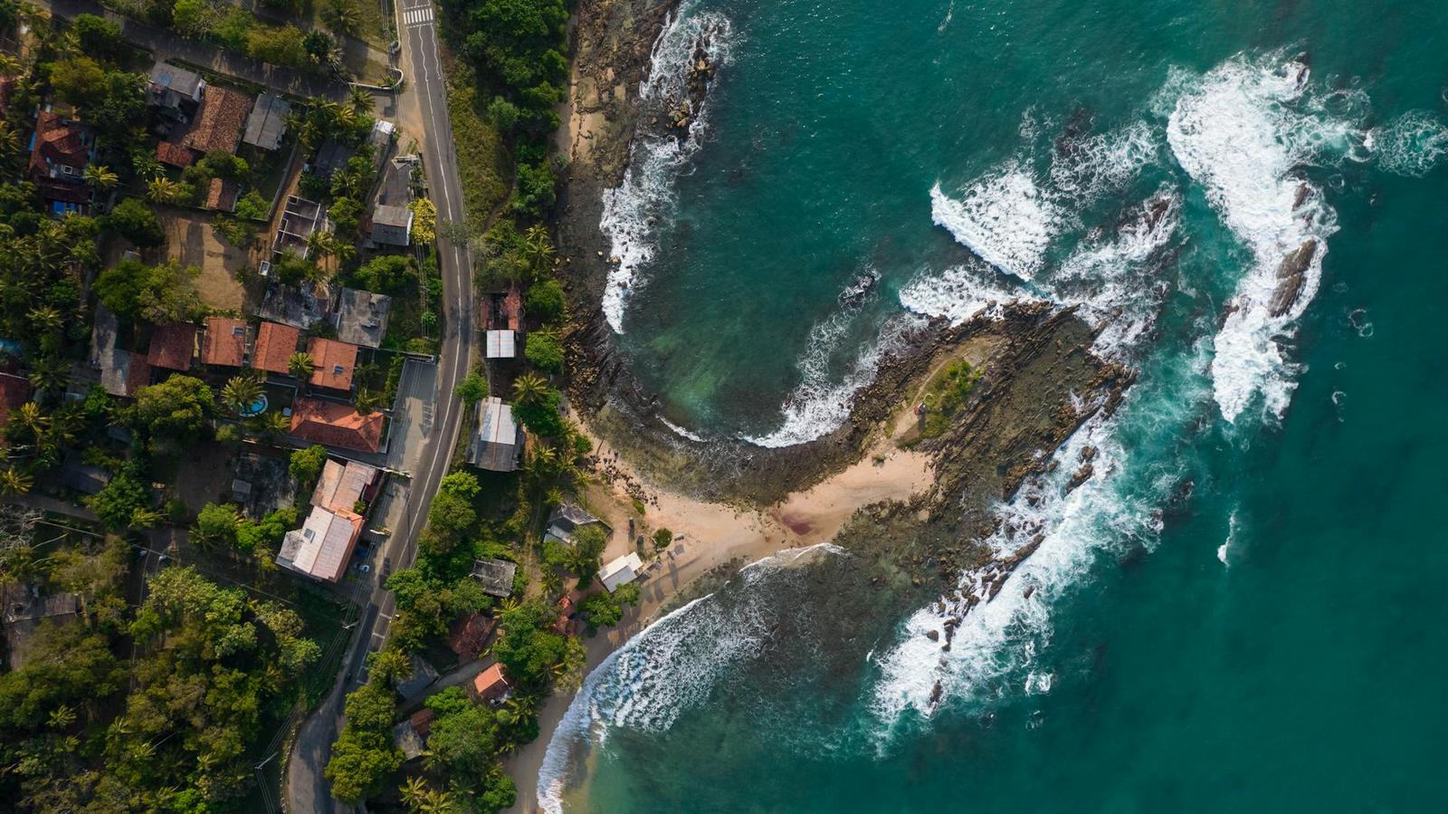 Aerial view of a rocky cove with a small beach beside a coastal road