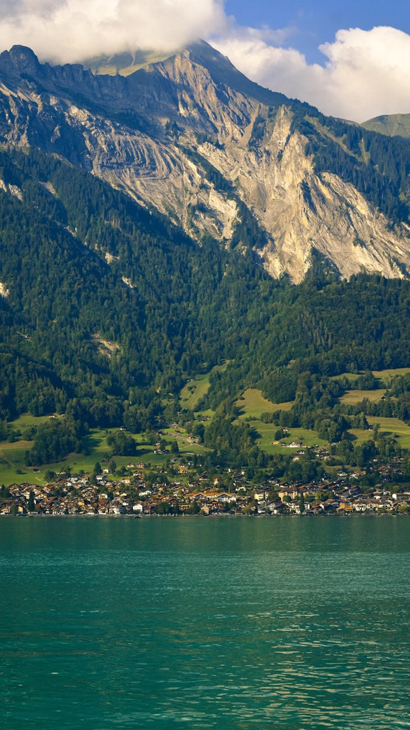 Lakeside village nestled below forested cliffs and rocky peaks