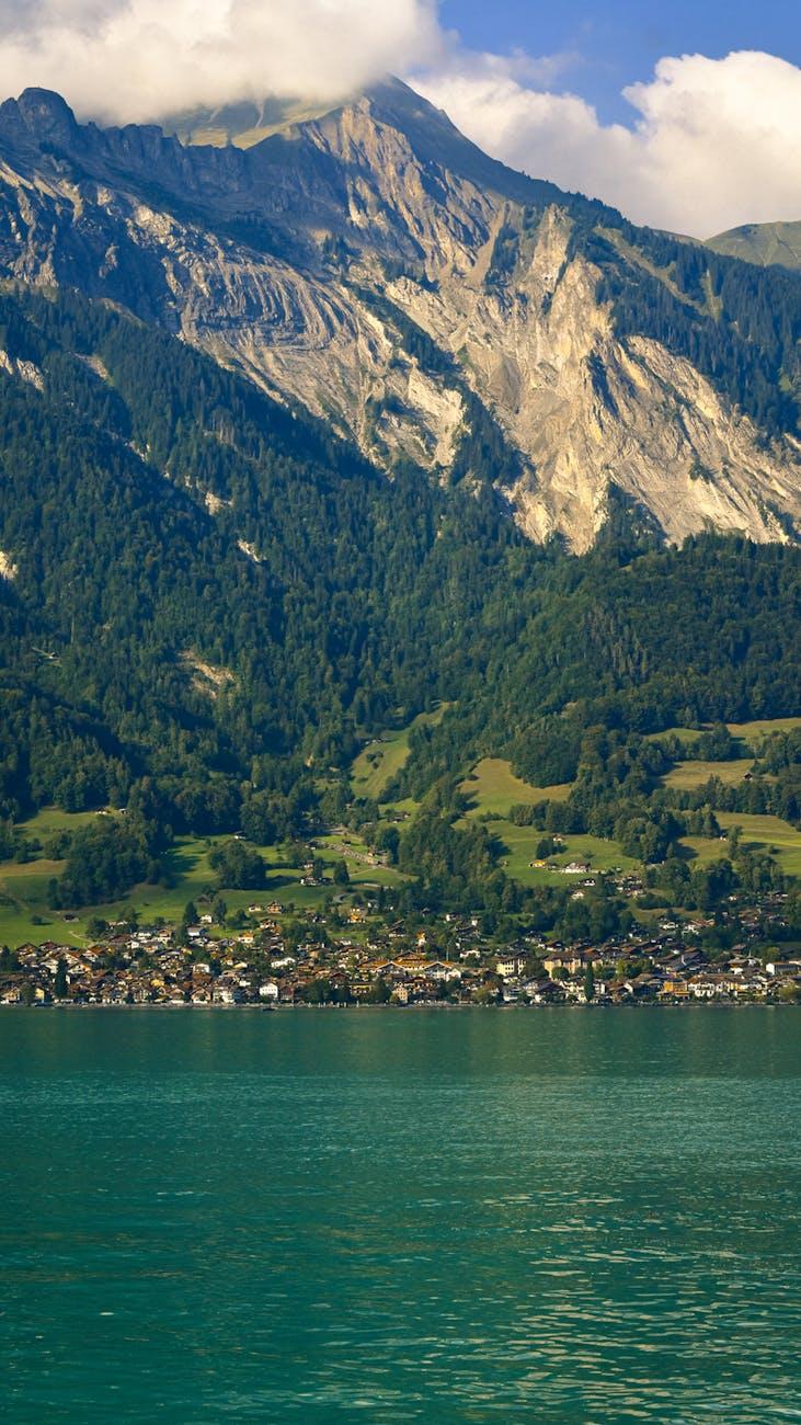 Lakeside village nestled below forested cliffs and rocky peaks